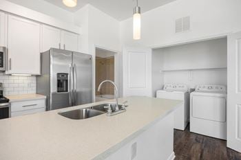 A white kitchen with stainless steel appliances and a white counter top